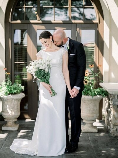 Groom kisses his bride's neck