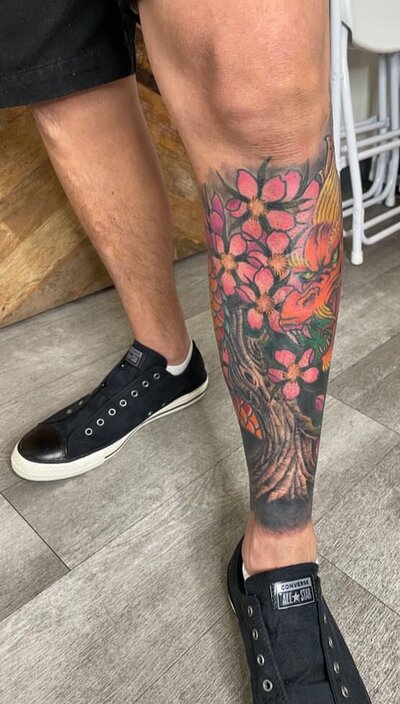 Pink floral tattoo in man's shin