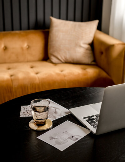 A cozy couch with a laptop and coffee, representing Tammy Aston’s inviting and calm coaching environment.