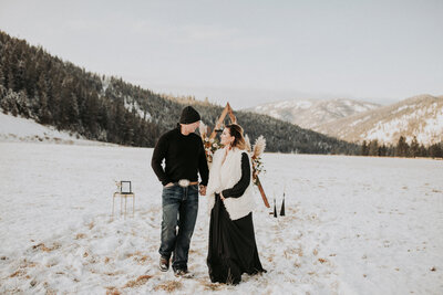 A bride and groom walk with one another at their elopement in snow lined mountains