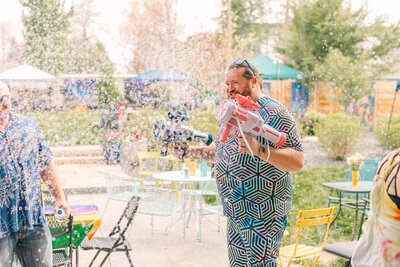 A man holding bubble machine smiling.