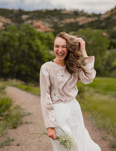 A girl laughs while getting blown by wind at her Senior Photo Session.