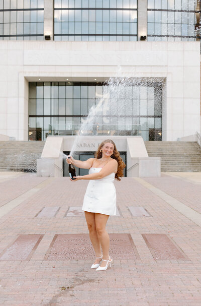 UA graduate popping champagne in front of Bryant Denny Stadium