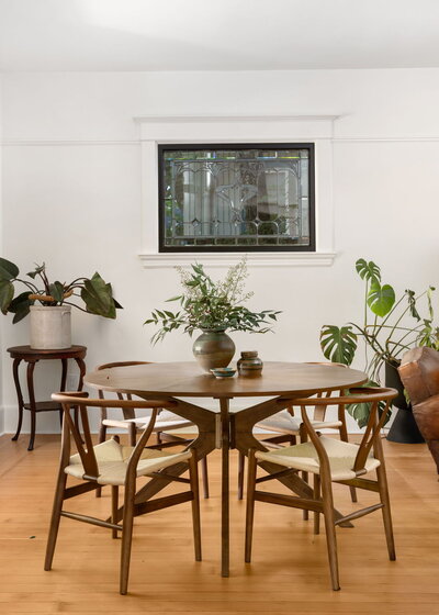 A dining room with a mid century modern wooden table and several house plants, representing an example of a home you can buy in portland with Stephanie as your realtor.
