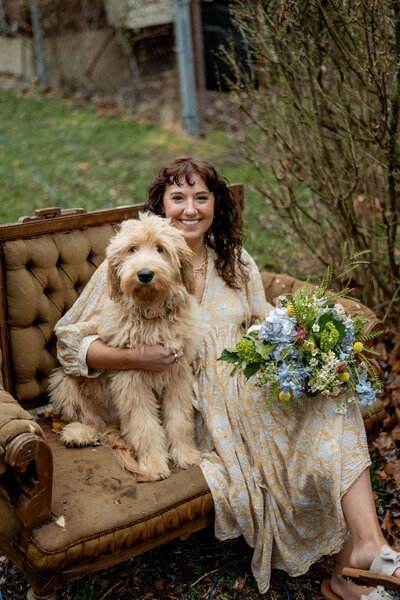 Pittsburgh wedding florist Heavenly Blooms sitting on couch outdoors holding floral bouquet and dog