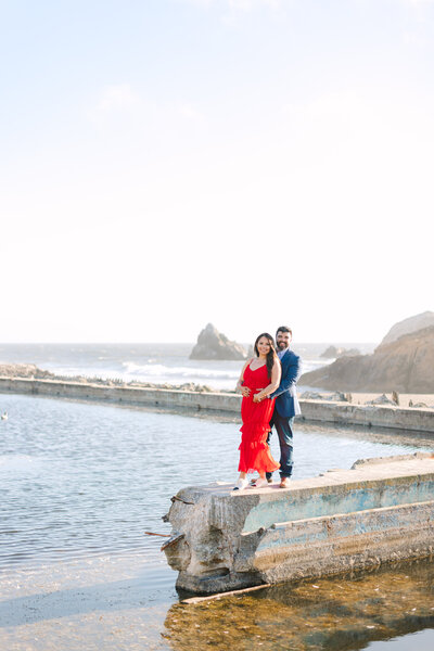 couple posing  at sutro baths ruins in san francisco with girl in red dress, photo by Anastasiya Photography - San Francisco Photographer
