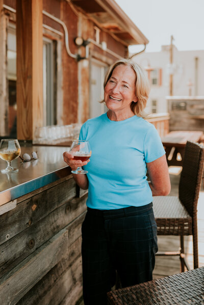 Smiling woman holding a drink on a restaurant patio during a lifestyle dating photography session in Minneapolis, showing relaxed personality and confidence.