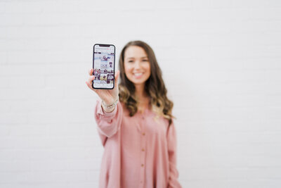 Amber Leach of Plymouth Marketing Agency Established By Her holing a phone up to the camera that displays a social media feed