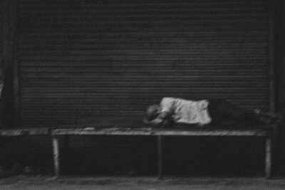 A somber image of a homeless person sleeping on a bench, symbolizing the challenges of homelessness and the impact of mental health struggles. This photo underscores the importance of supporting mental well-being initiatives.