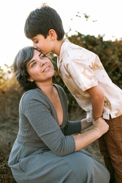 Portland Photographer, Evelynne Gomes Greenberg receives a kiss from her son on the temple.