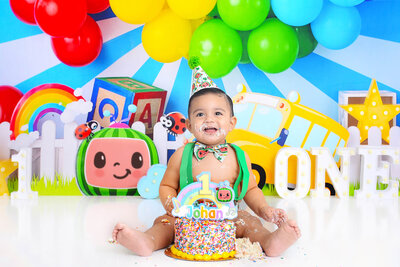boy smiles at his cocomelon themed cake smash photography session
