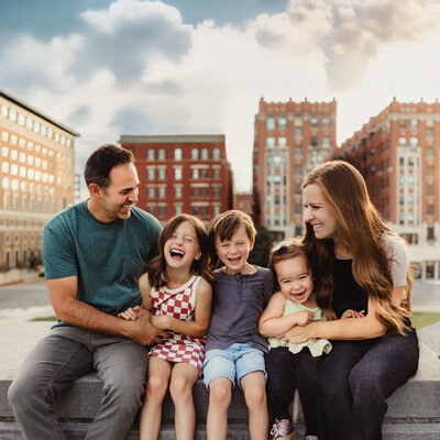 family of five smiling  in front of sand dunes