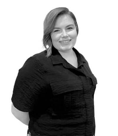Senior Stylist with short wavy hair wearing a textured black shirt, radiating confidence and creativity in hairstyling services.