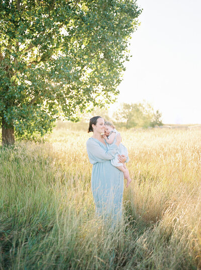 Expectant mother, snuggling toddler in field at sunrise, captured by Edmonton maternity photographer, Kahla Kristen