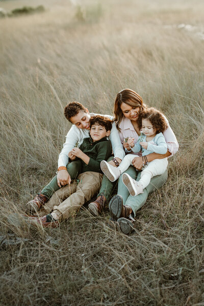 Family photography family sitting close together woman holding younger child in field in Tampa Bay, Florida Nadine B Photography