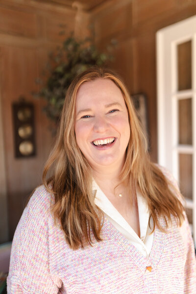 headshot of woman in wood paneled room smiling at camera