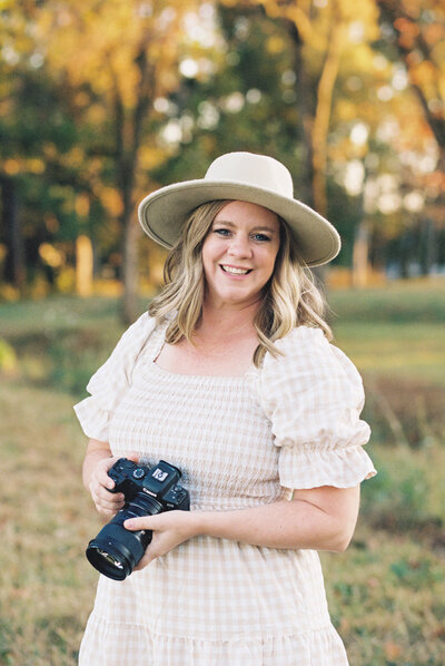 family photographer in madison al by whitney briscoe - photographer holding camera wearing a hat in the fall