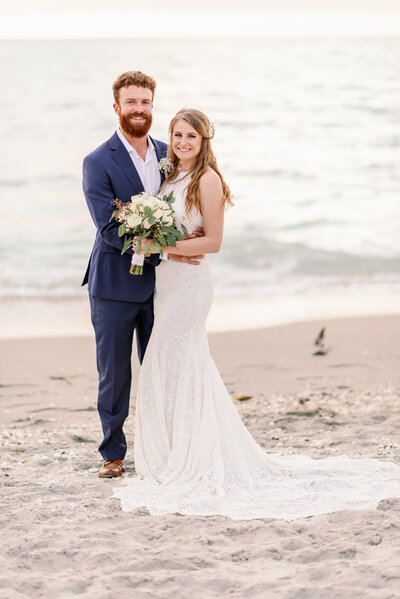 Bride and groom standing on a beach on Captiva Island looking at the camera and smiling
