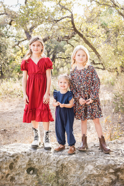 three girls standing together on a rock