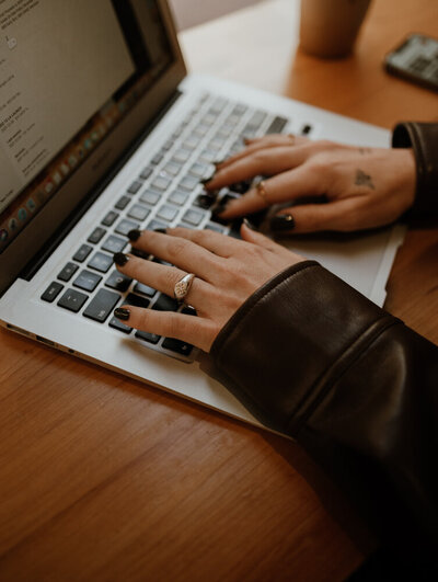 Female hands typing at a macbook pro laptop