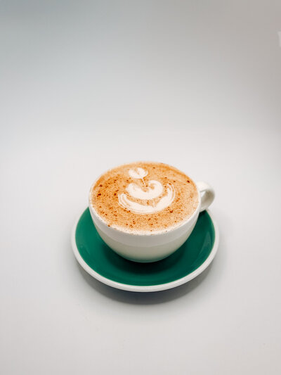Piña Colatte specialty iced latte from Quigley Coffee Co, topped with cold foam and garnished with a pineapple leaf.