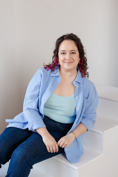 laura sits on white steps with a soft smile