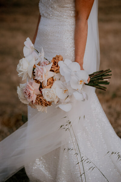 Close up of bride holding a wedding bouquet  of roses & orchids
