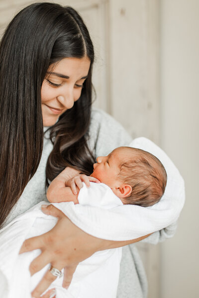 Mother holding newborn, looking down affectionately