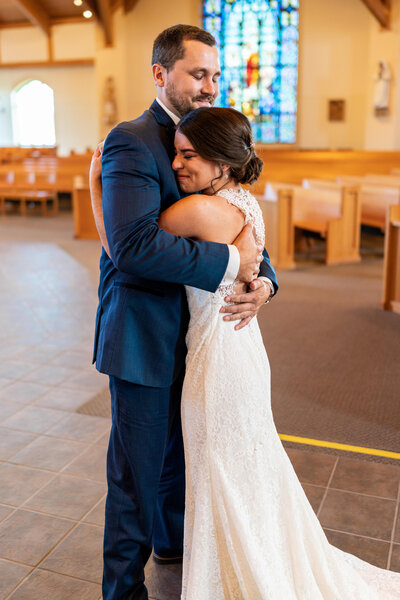 Bride and groom hug in church after first look.