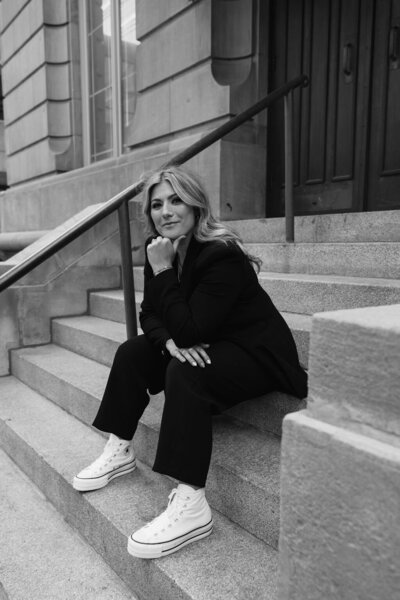 Calgary Realtor Leigh Kormos in black sitting on the front steps