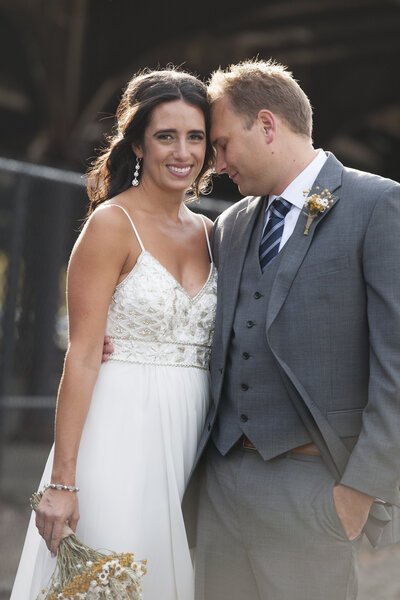 A person resting their head on their partner's as they smile on their wedding day 