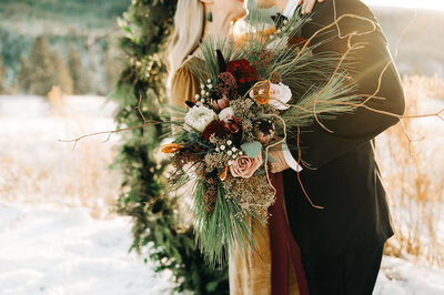 Stunning winter bridal bouquet with pink, burgundy, and pops of gold created by J.A.M Florals, contemporary and playful Kelowna wedding florist, featured on the Brontë Bride Vendor Guide.