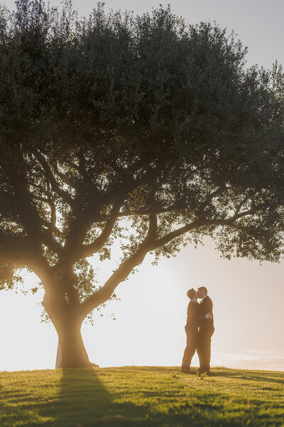 two grooms kiss at their gay wedding at a golf course