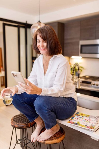 woman smiling at her phone sitting on the counter