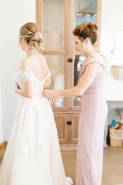 Bride's mom zipping up the back of her wedding dress
