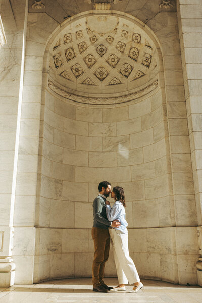 a couple kissing and embracing outside of the new york public library 