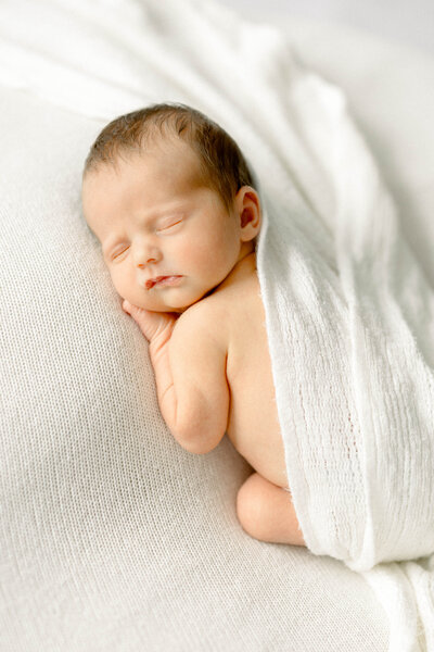 Newborn baby sleeping peacefully on neutral blanket during studio session with Sandra Vallejo Photography in Miami.