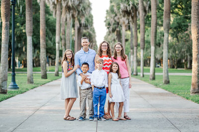 A family poses for a photography session in a city park with palm trees in Savannah, GA.
