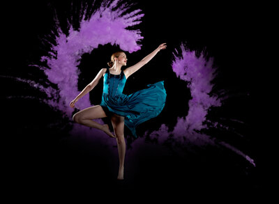 A teenage girl dances with her dress flowing and purple smoke behind her. 