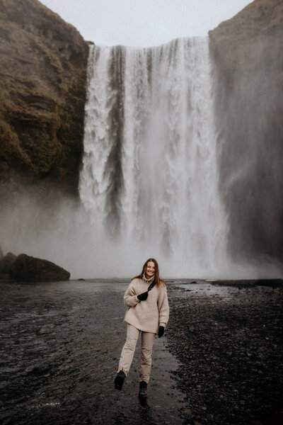 en elopement fotograf står framför ett vattenfall i Island