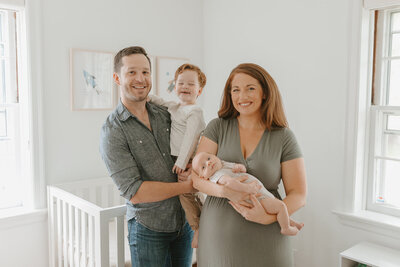 Brunette mother and father holding their young sons during newborn session in St. Louis