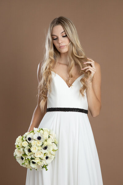 Bride wearing a black rhinestone belt and holding a black and white bouquet