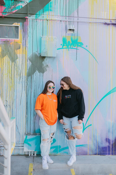 Two friends chatting in front of a wall.