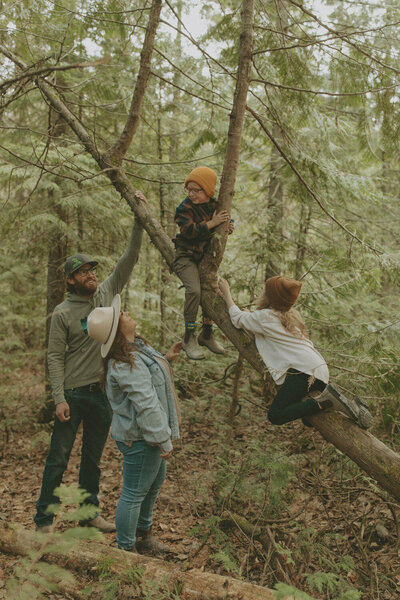 family hanging around a tree in the forest