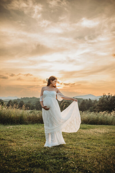 A pregnant mother in a white dress at sunset dancing in Tazewell, Virginia.