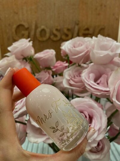 cream glossier bottle with gold engraved writing 