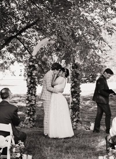 Two brides holding hands, laughing while standing in a park