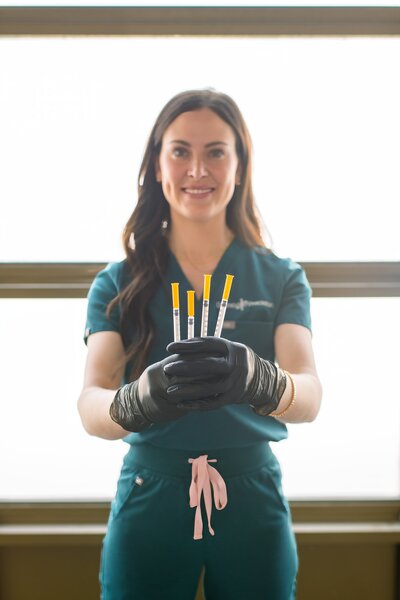 Nurse Injector posing for a branding shot holding needles in her hand