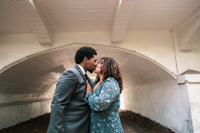 Sean and Graciela kissing under a white building