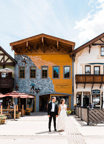 A couple stands in front of colorful buildings in leavenworth photographed by pnw adventure elopement photographer amy galbraith